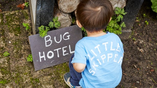 Child crouching in front of a bug hotel